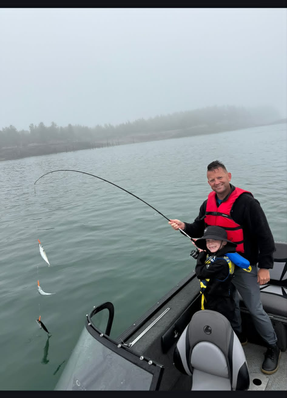 Father and son hooked into fish on a foggy saltwater trip