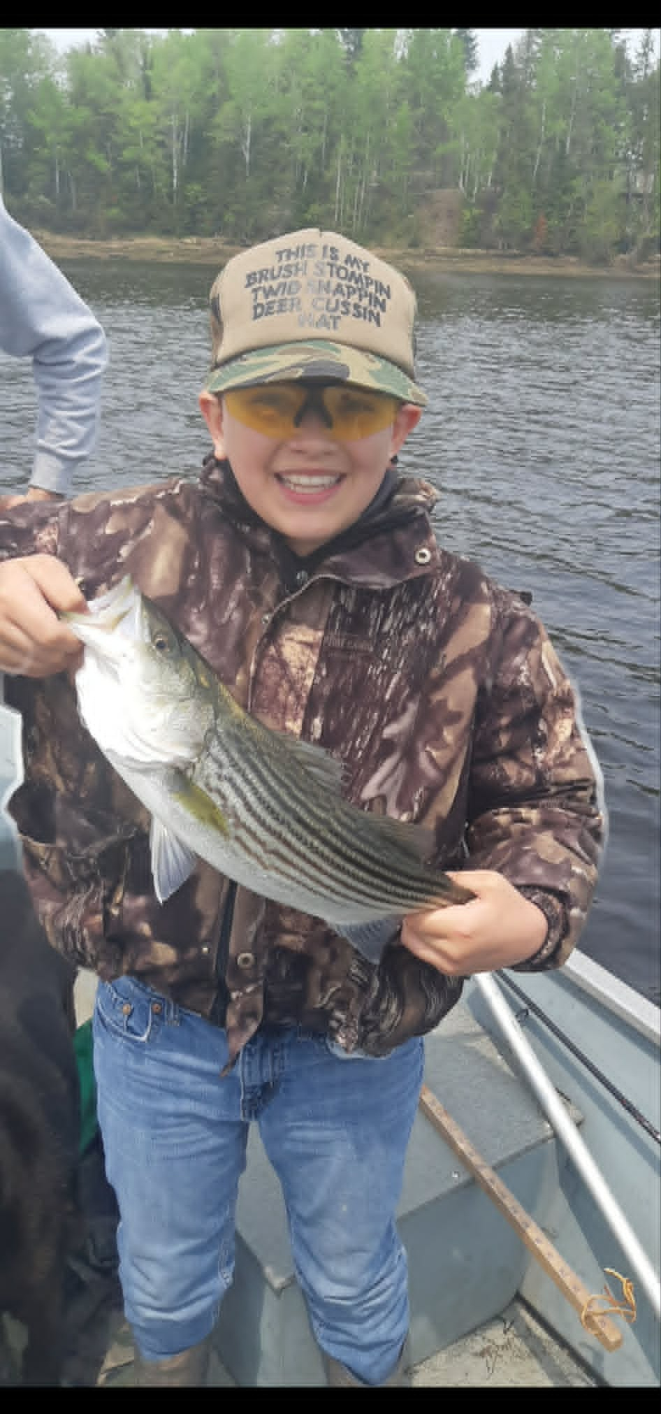 Young angler with a striped bass on the river