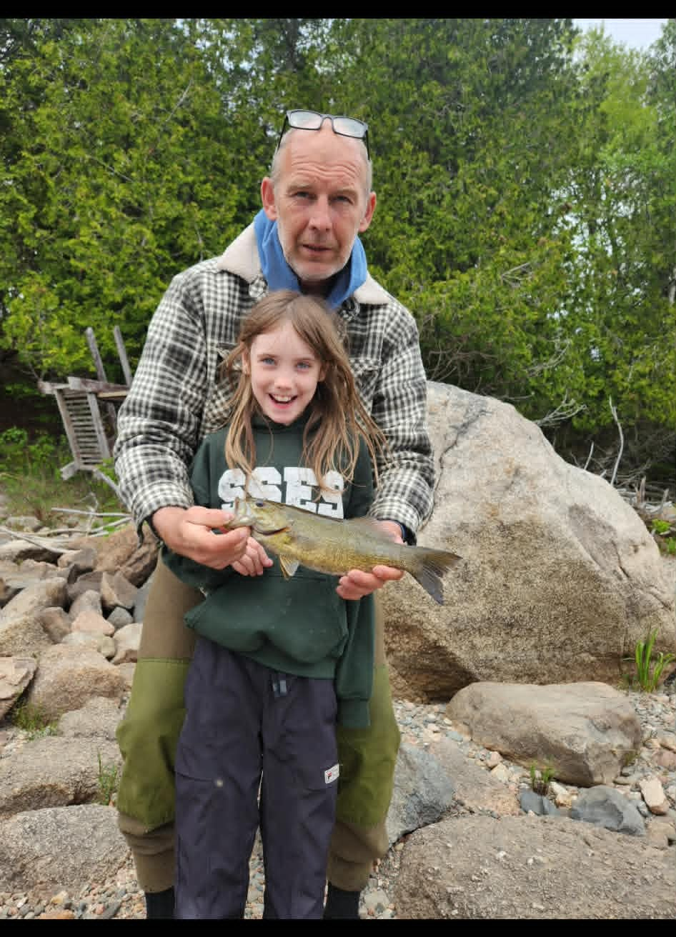 Guide helping a young girl hold her smallmouth bass catch
