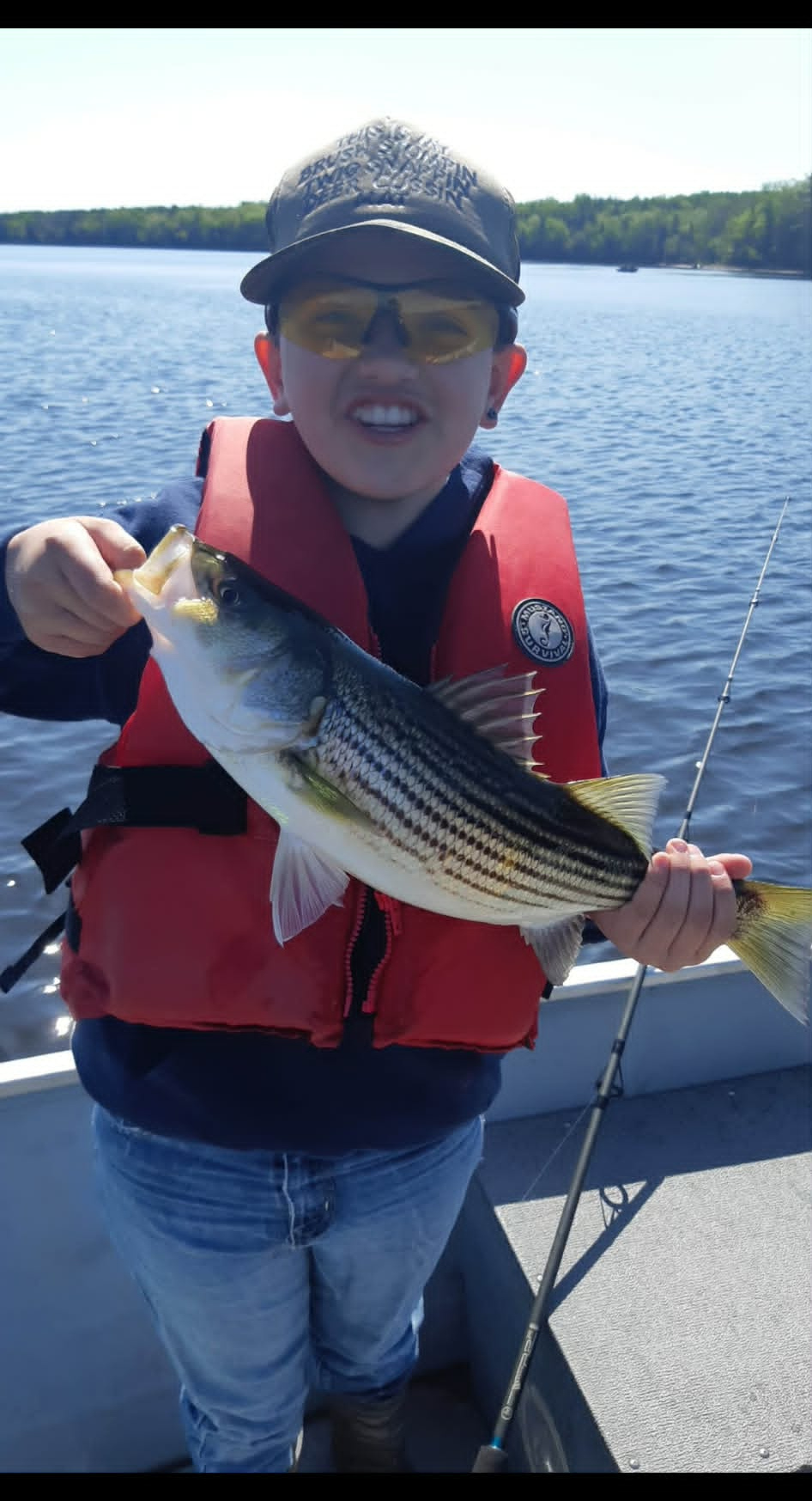 Young angler holding a striped bass on a sunny day